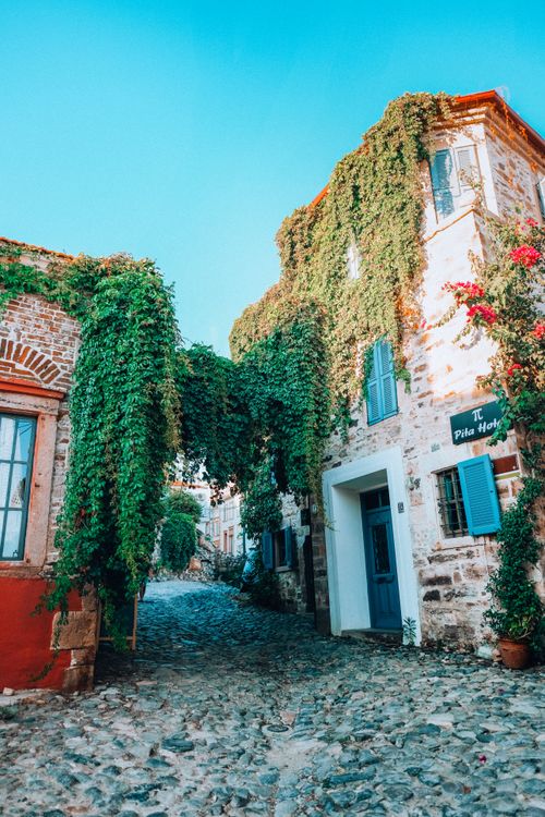Free Picturesque stone street with ivy-covered historic buildings under a clear blue sky. Stock Photo