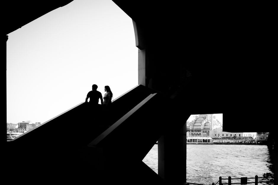 A silhouette of a couple standing on a bridge in Istanbul with a mosque view.