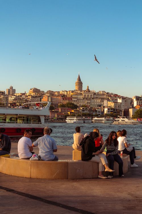 Free People enjoying a sunny day by the waterfront with Istanbul's iconic skyline and Galata Tower in view. Stock Photo