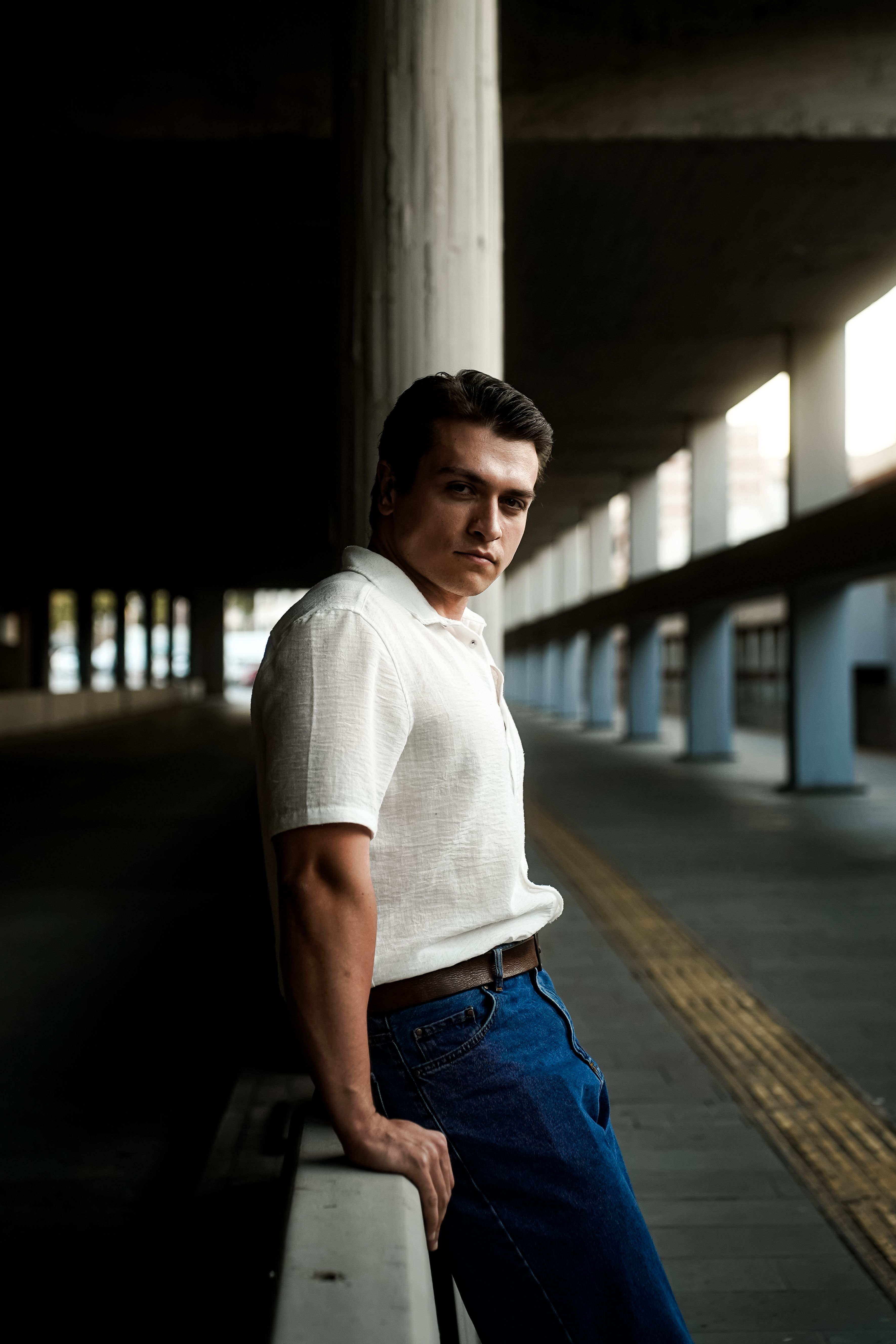 A man in jeans leaning against a concrete wall · Free Stock Photo