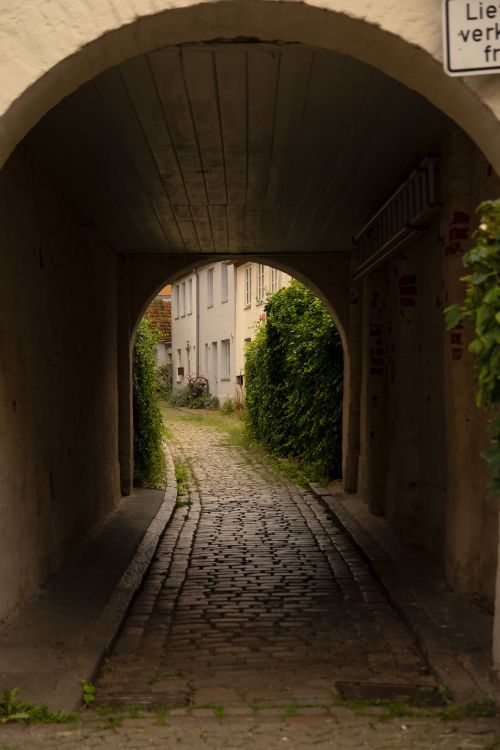 Free Charming cobblestone alley through an archway in Lübeck, Germany, showcasing medieval architecture. Stock Photo
