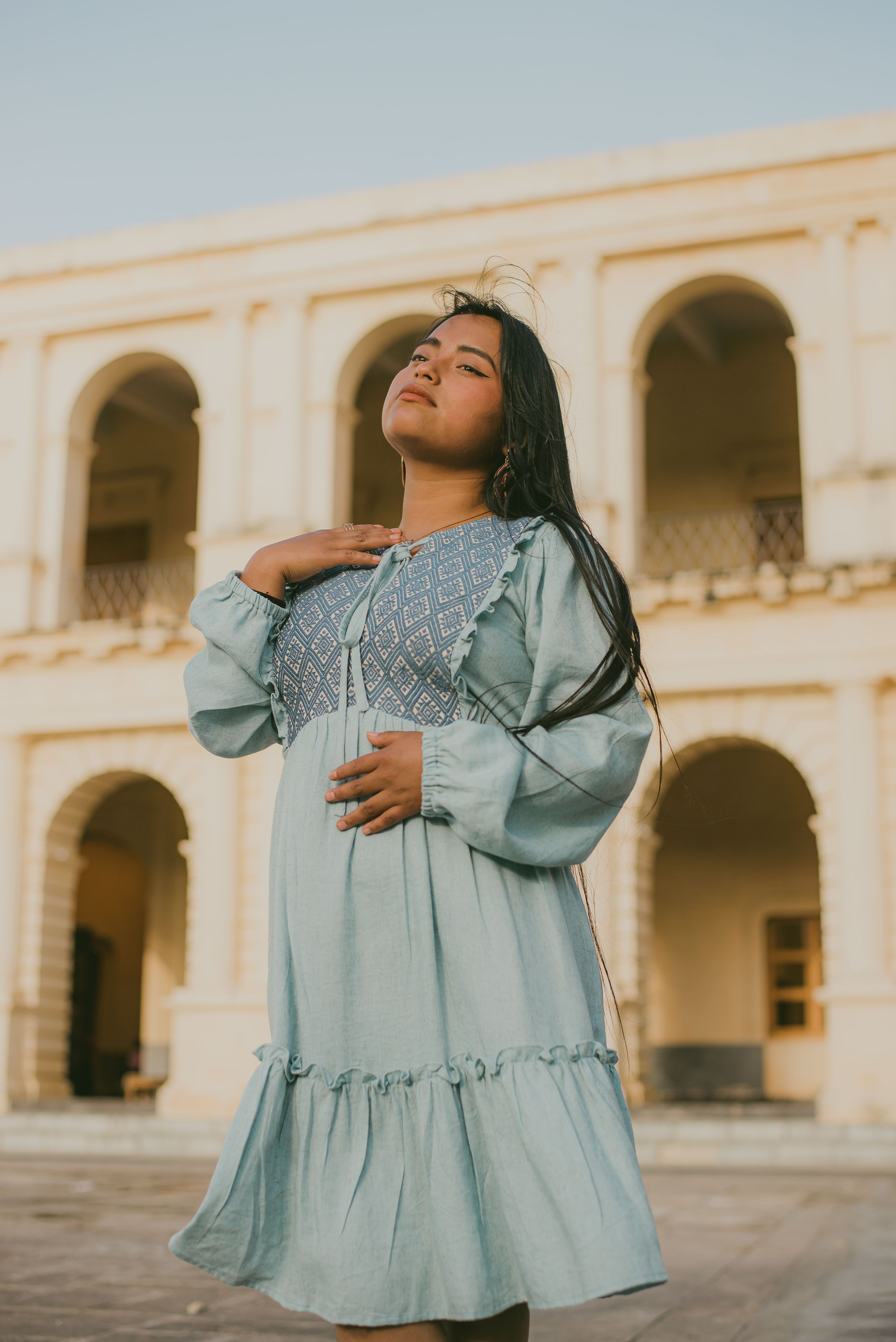 A woman in a blue dress stands in front of a building · Free Stock Photo