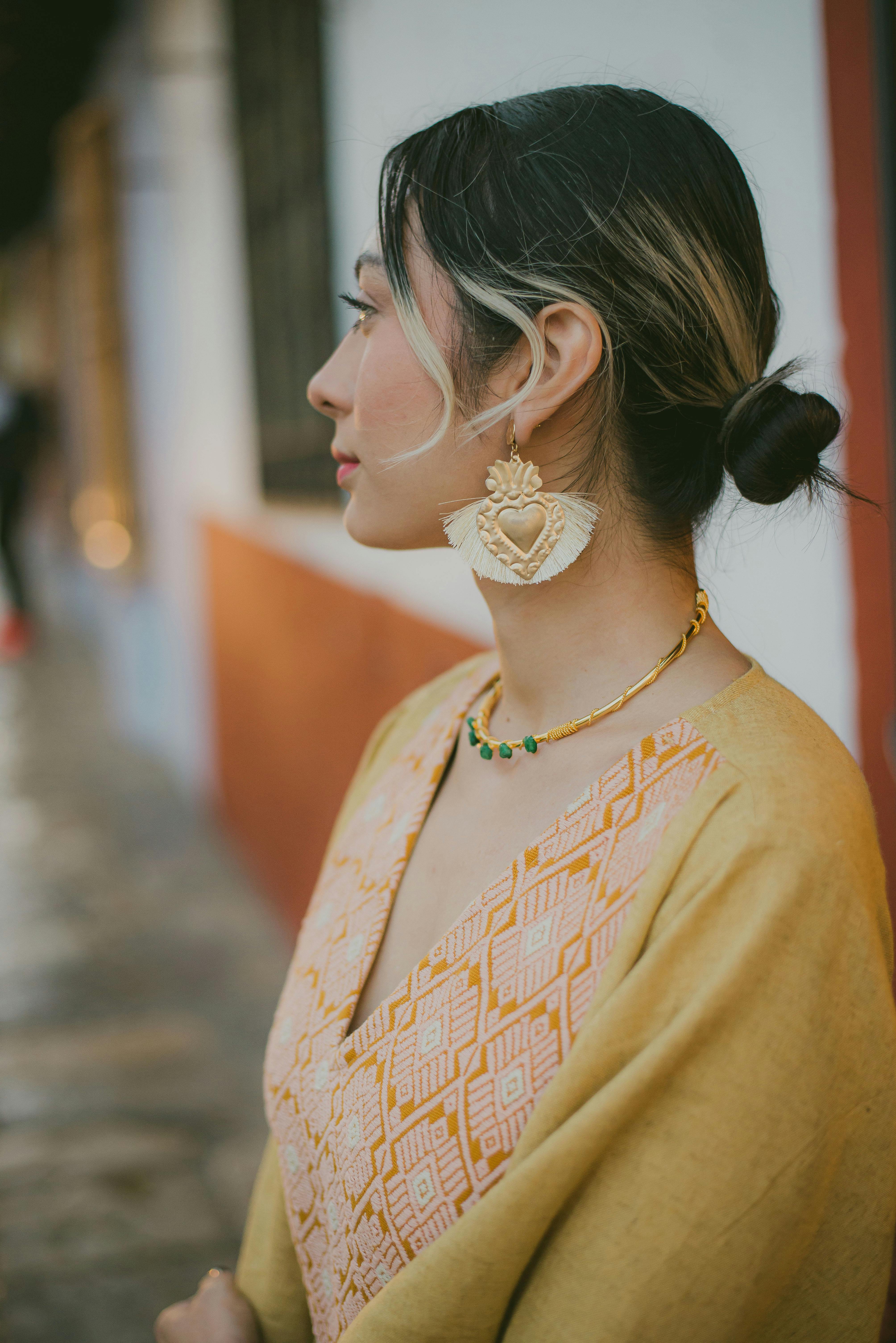 Side view of a woman wearing traditional jewelry and clothing outdoors.