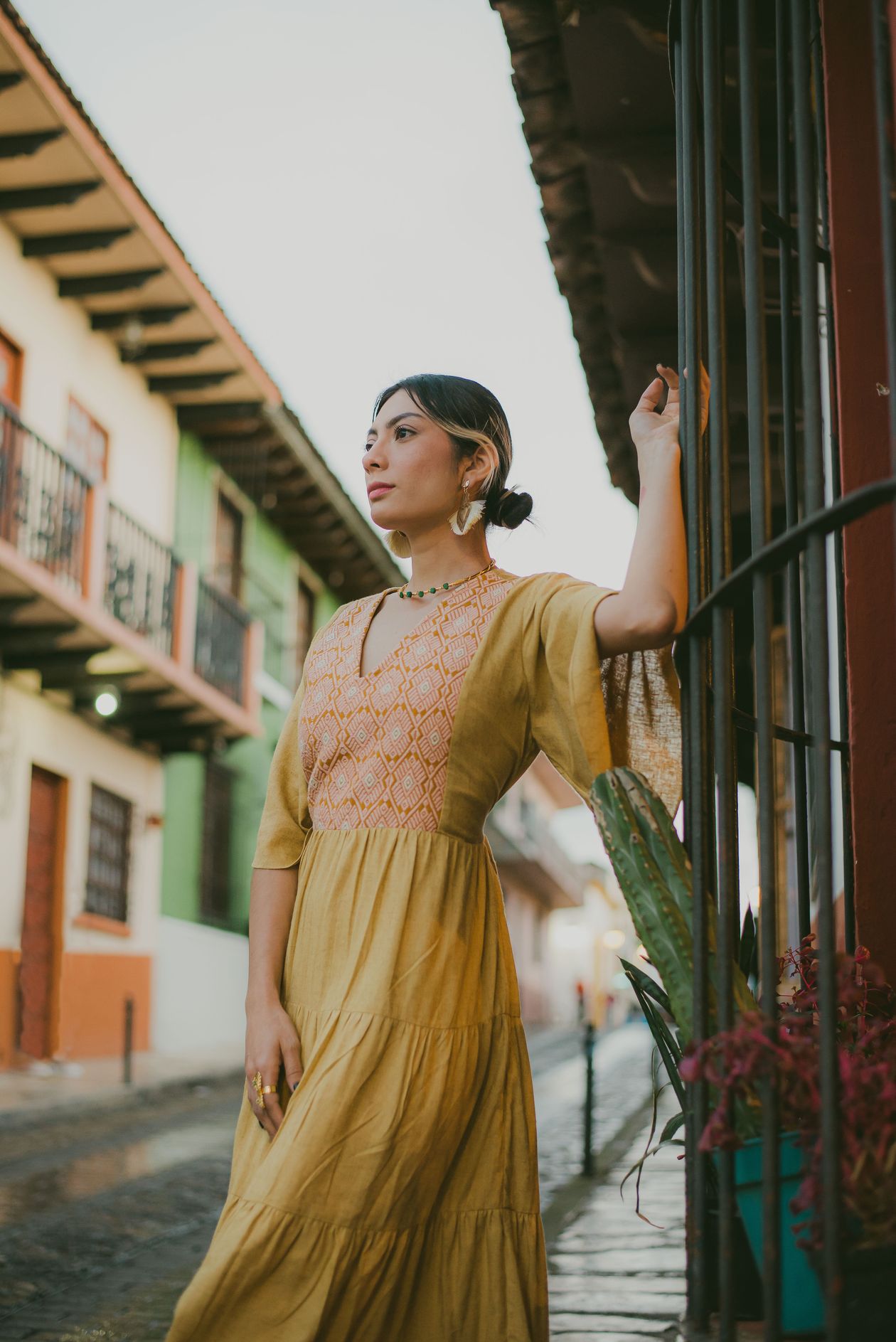 Woman in a mustard tiered boho dress on a colorful street