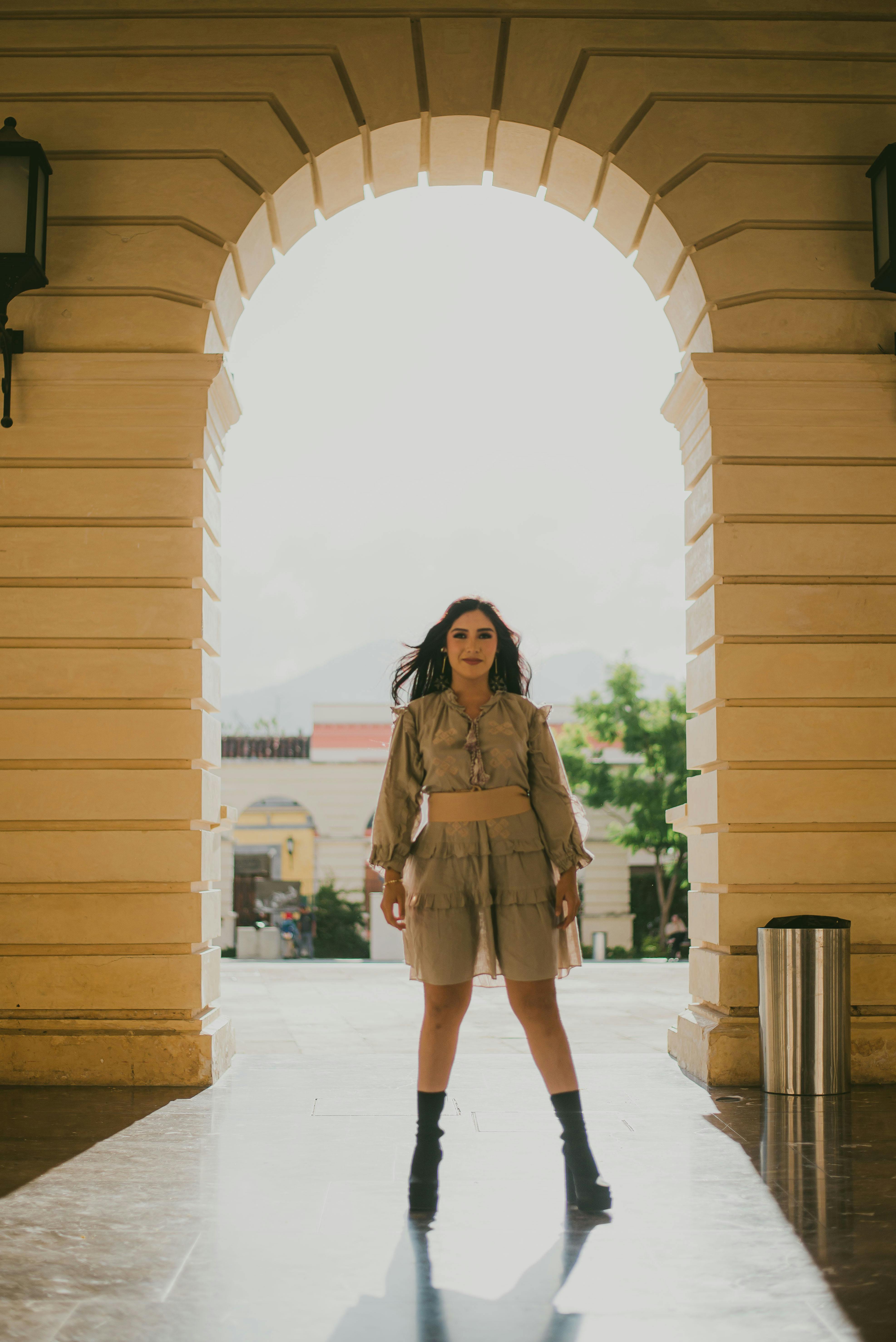 a woman in a beige outfit standing in an archway