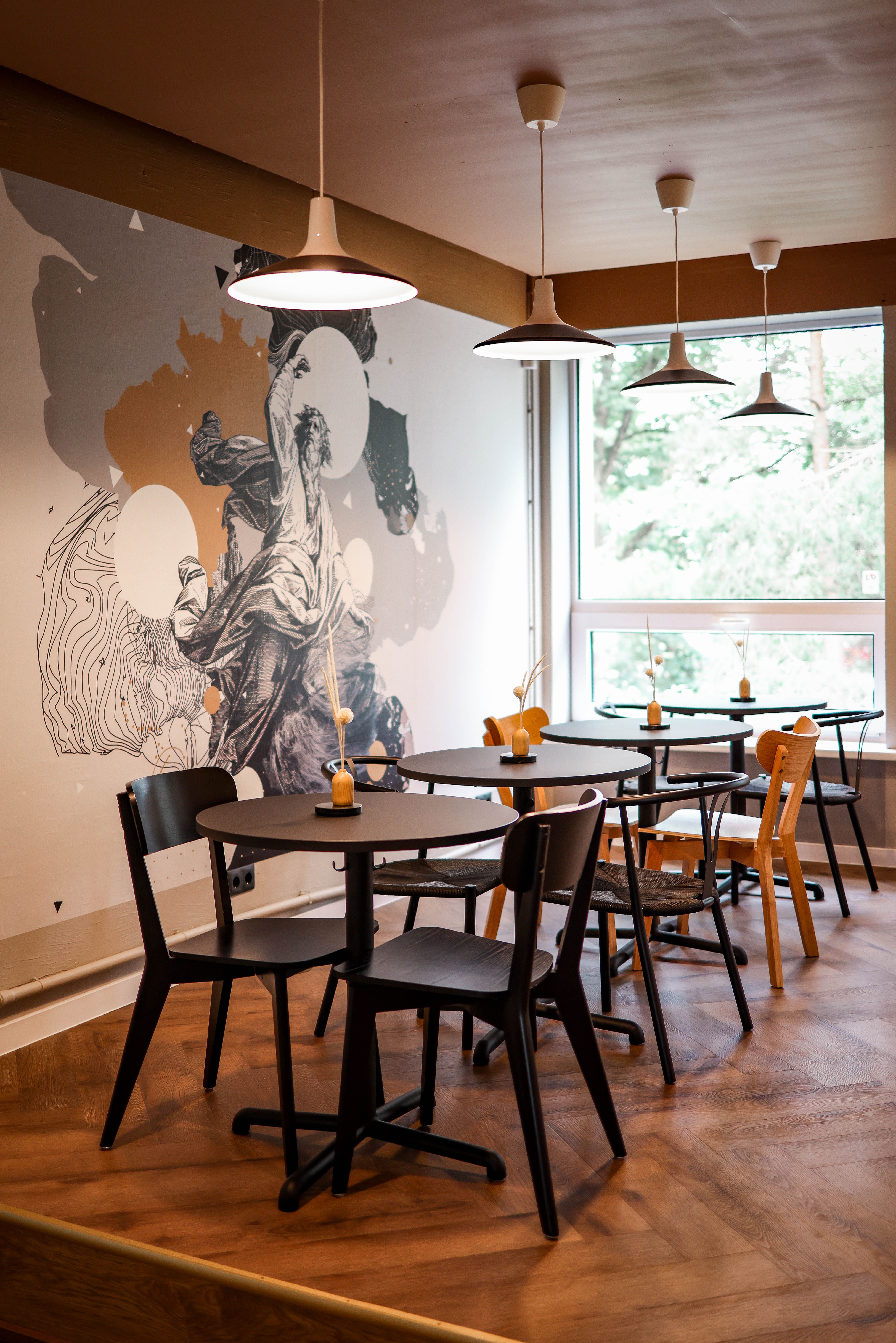 A restaurant with wooden tables and chairs and a mural on the wall ...