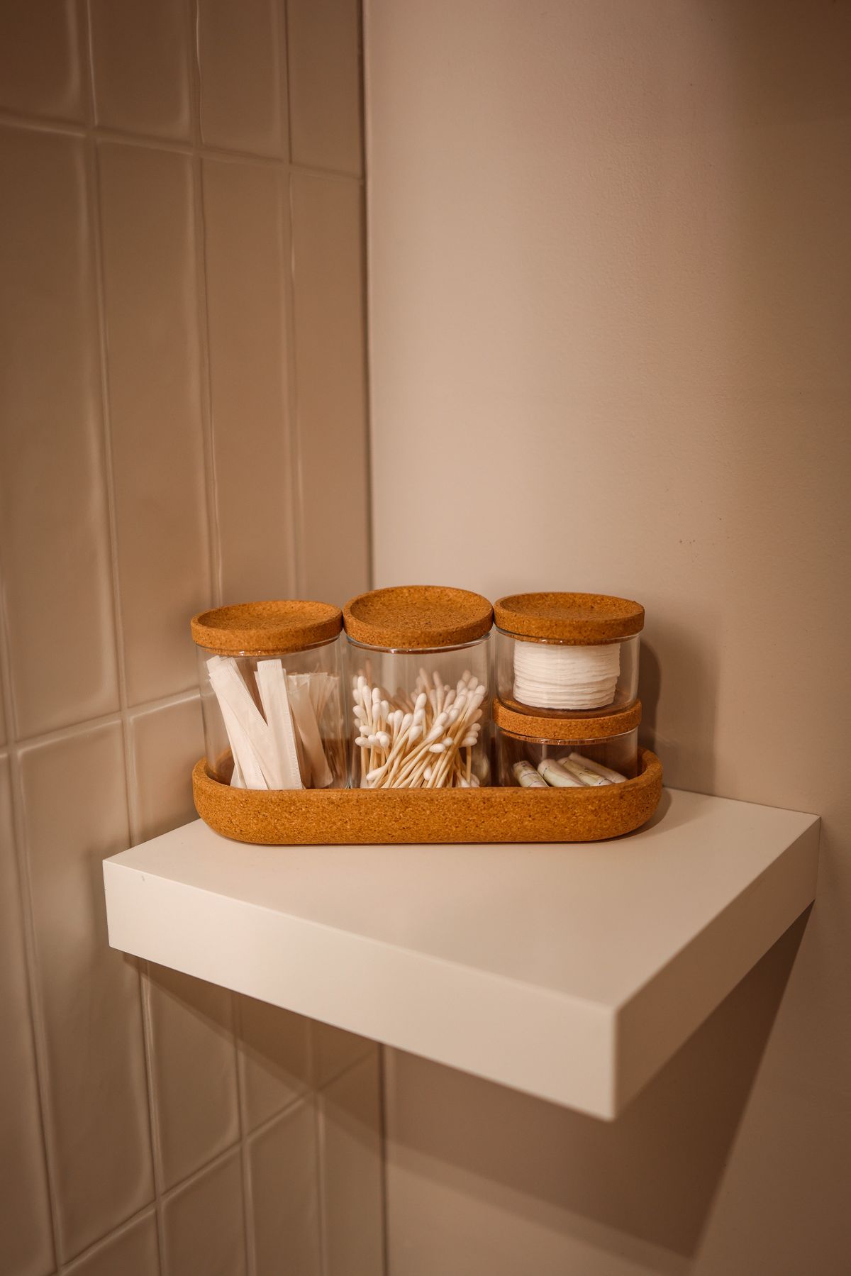 Glass jars with bathroom essentials and a toothbrush neatly arranged on a shelf