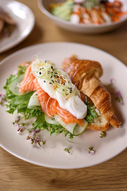 Delicious gourmet croissant sandwich with salmon, sprouts, and boiled egg, perfect for a fresh meal.