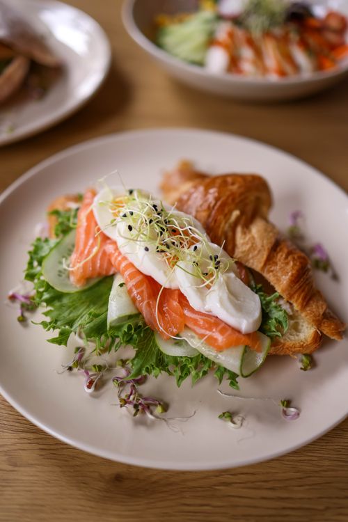 Free Tasty breakfast featuring a croissant, fresh salmon, and poached egg on lettuce. Stock Photo