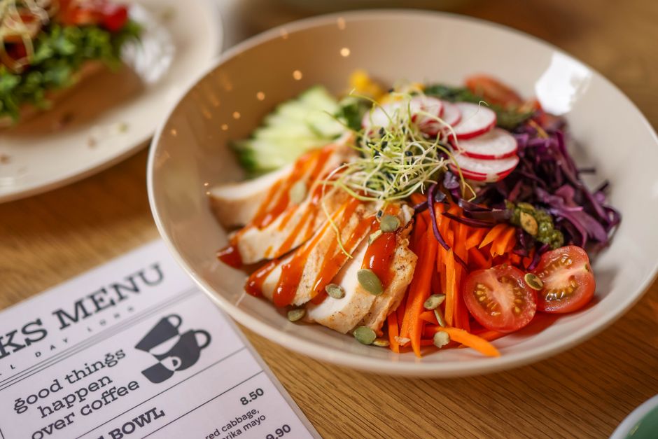 A vibrant salad bowl featuring fresh vegetables and grilled chicken on a wooden table.