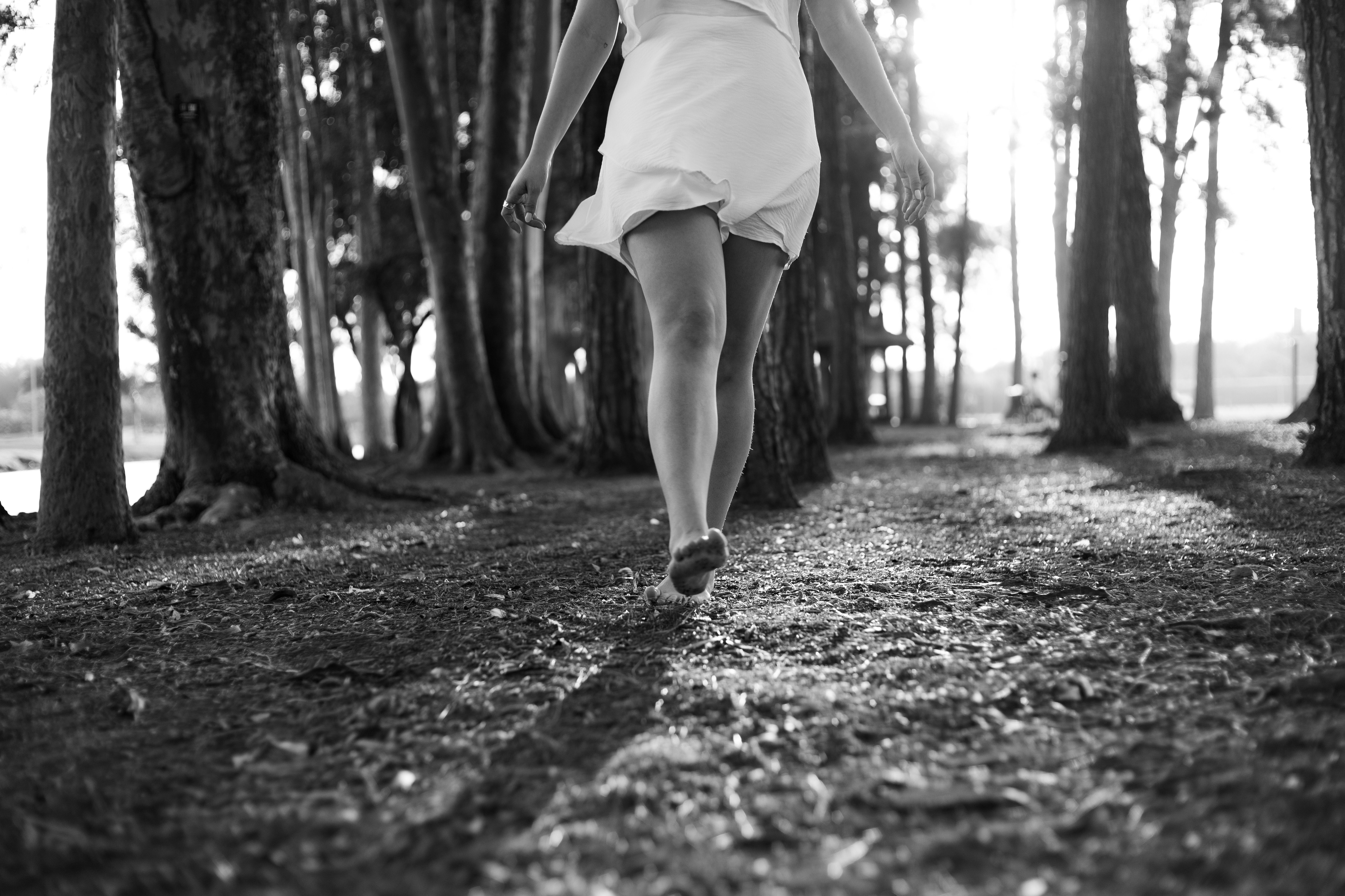 person walking slowly through a forest path, dappled sunlight