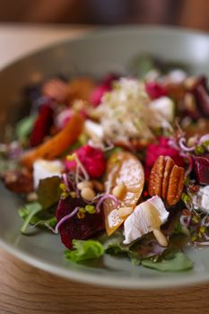 Fresh and nutritious mixed leaf salad with pecans, cheese, and vibrant vegetables on a plate.