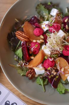 Delicious and colorful mixed salad with fresh ingredients, including beetroot, goat cheese, and nuts.