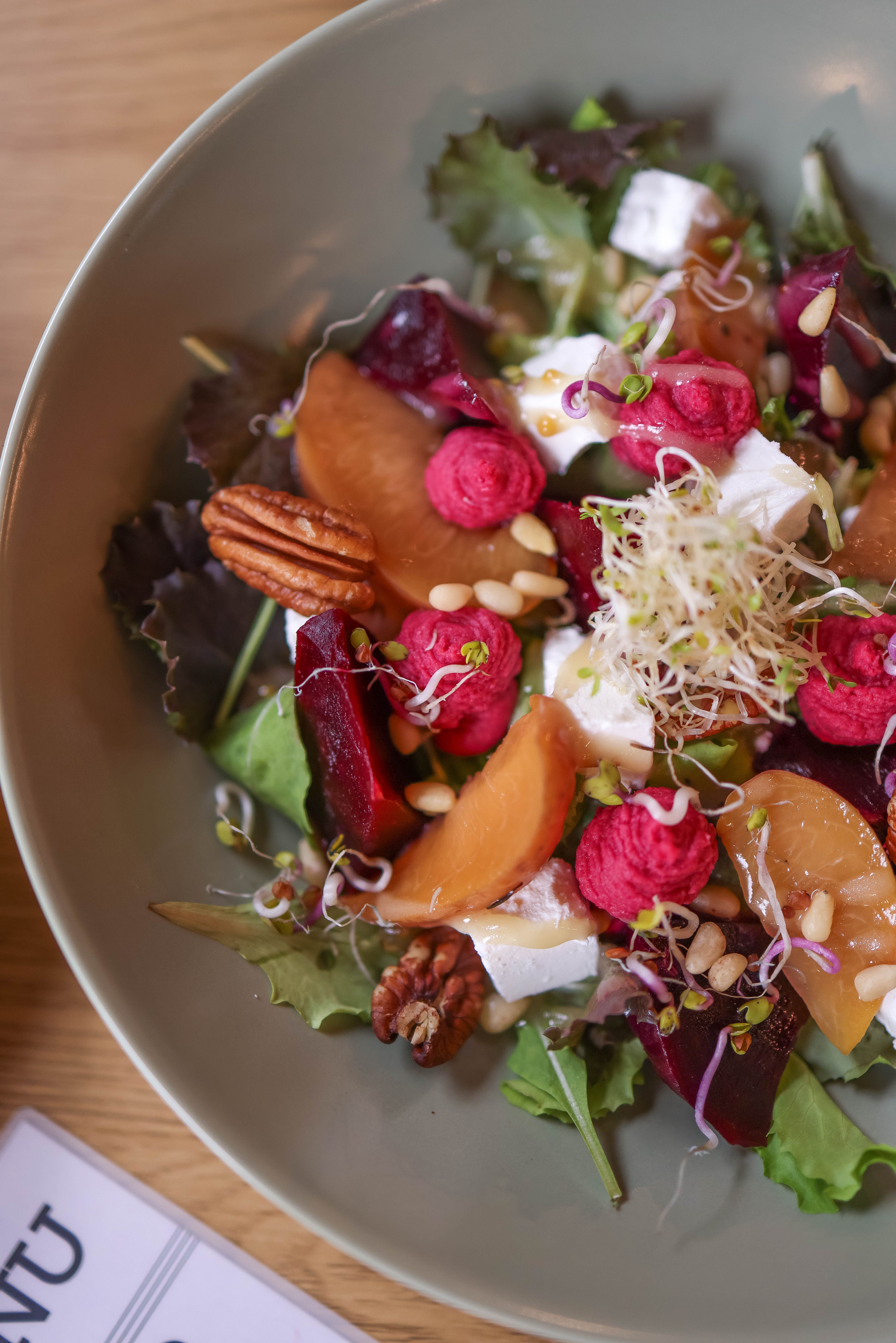 Colorful vegetable salad with beets, feta, nuts, and sprouts on a plate.