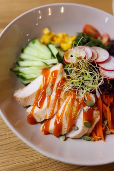 A colorful and nutritious grilled chicken salad with fresh vegetables and vibrant dressing.