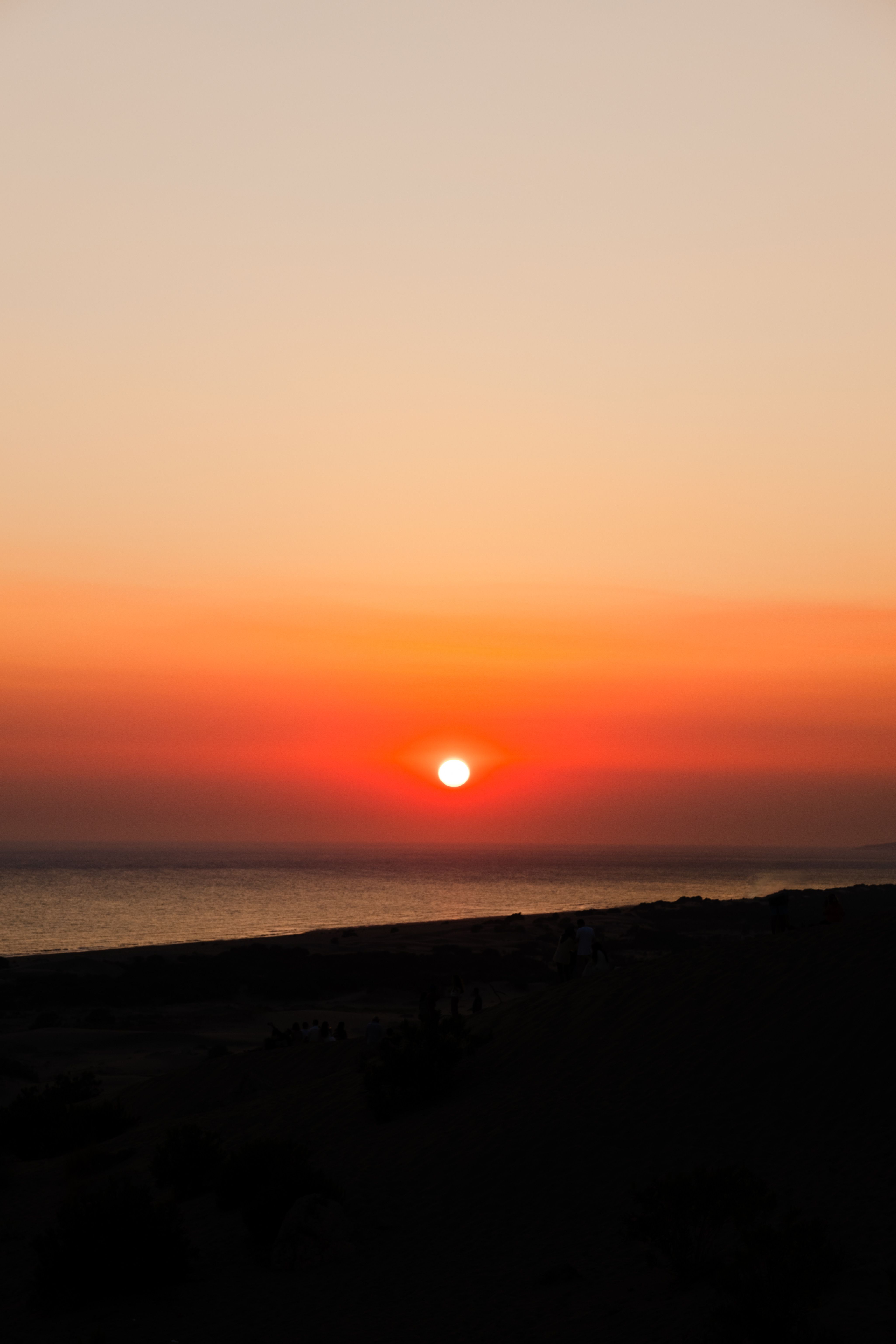 A sunset over the ocean with a bright orange sky · Free Stock Photo