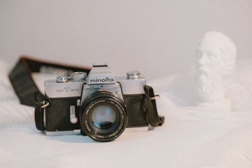 Free Vintage Minolta SR-T 303 camera with a lens, placed on a soft textured surface, showcasing classic photographic equipment. Stock Photo