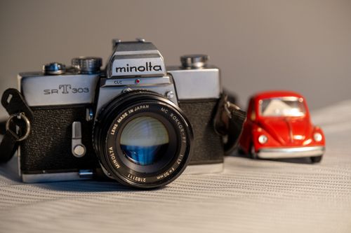 Free A classic Minolta analog camera alongside a retro red toy car in a still life composition. Stock Photo