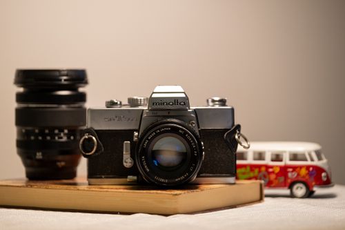 Free A classic Minolta film camera with a lens and toy van, embodying nostalgia and vintage charm. Stock Photo