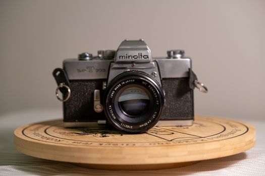 A classic Minolta film camera displayed elegantly on a round wooden platform.