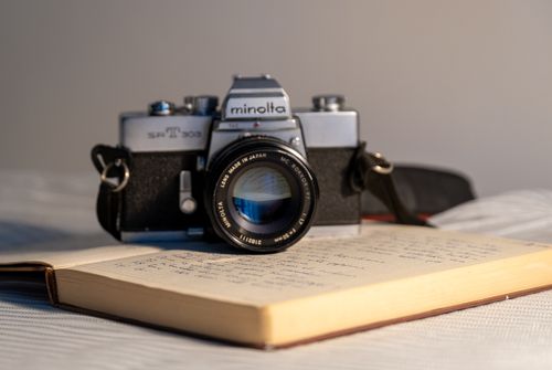 Free Classic Minolta camera displayed on an open notebook, evoking nostalgia and artistic charm. Stock Photo