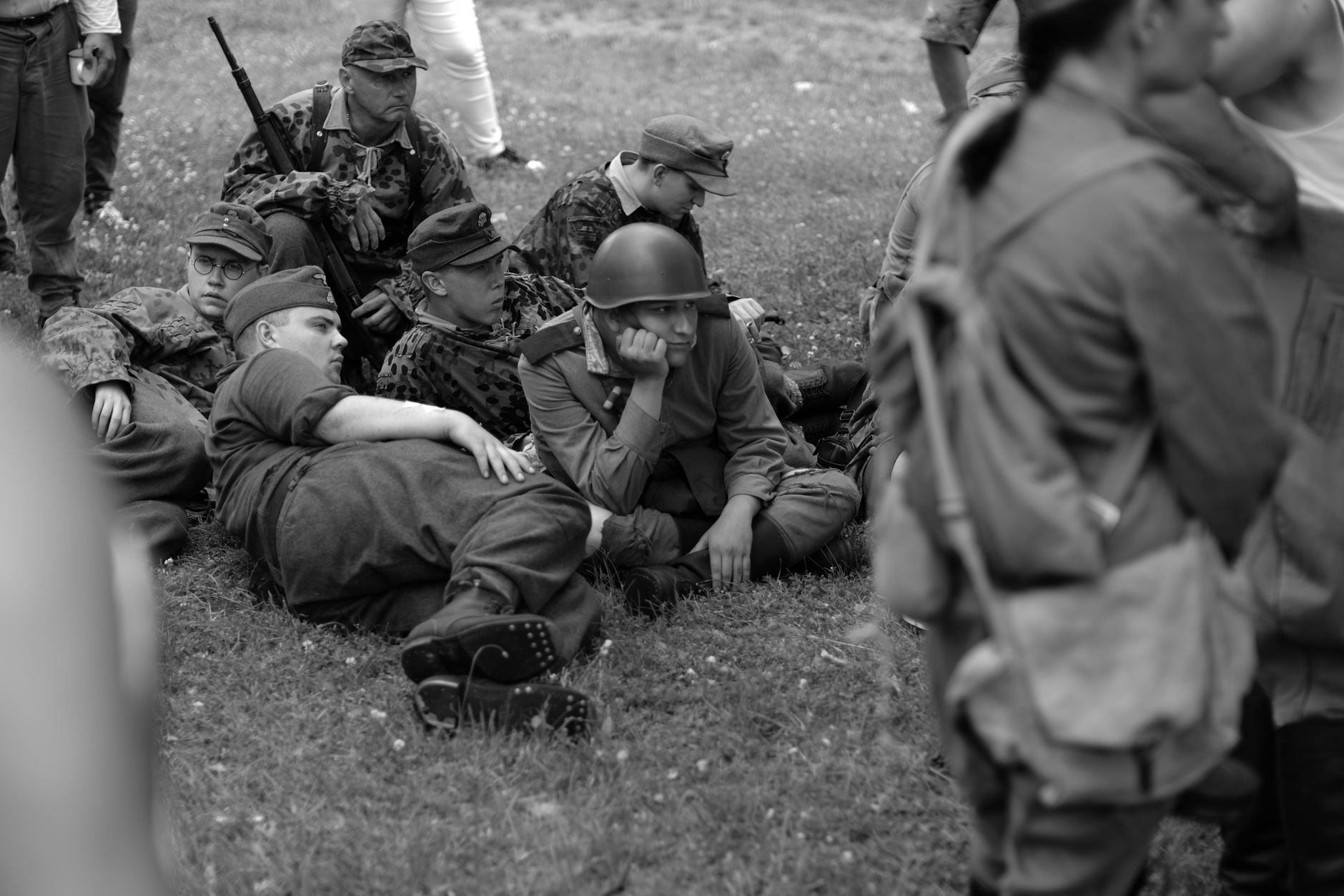 Group of soldiers in historical uniforms during a reenactment, resting outdoors.