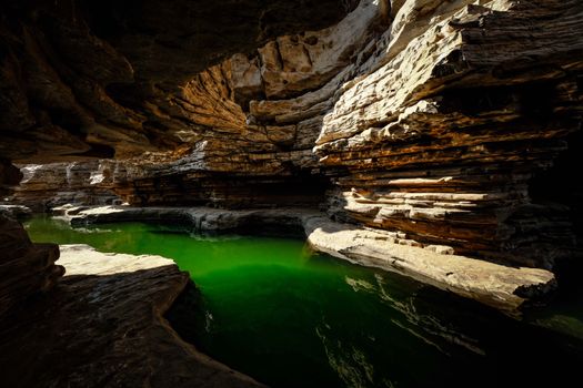 Stunning limestone cave showcasing dramatic rock formations and vibrant green water.