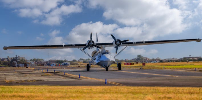 A vintage seaplane with dual propellers on a runway under a clear blue sky.