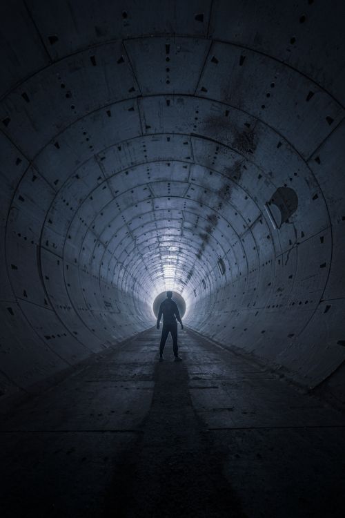 Free A silhouetted man stands in a dark tunnel, evoking mystery and intrigue. Stock Photo