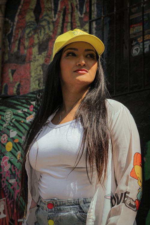 Free Fashionable woman poses in front of colorful graffiti wall, exuding urban style. Stock Photo