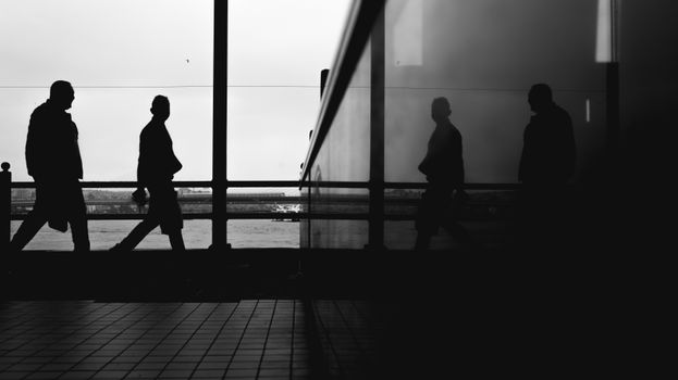 Silhouetted people reflected in glass at sunset in İstanbul, capturing a moody urban scene.