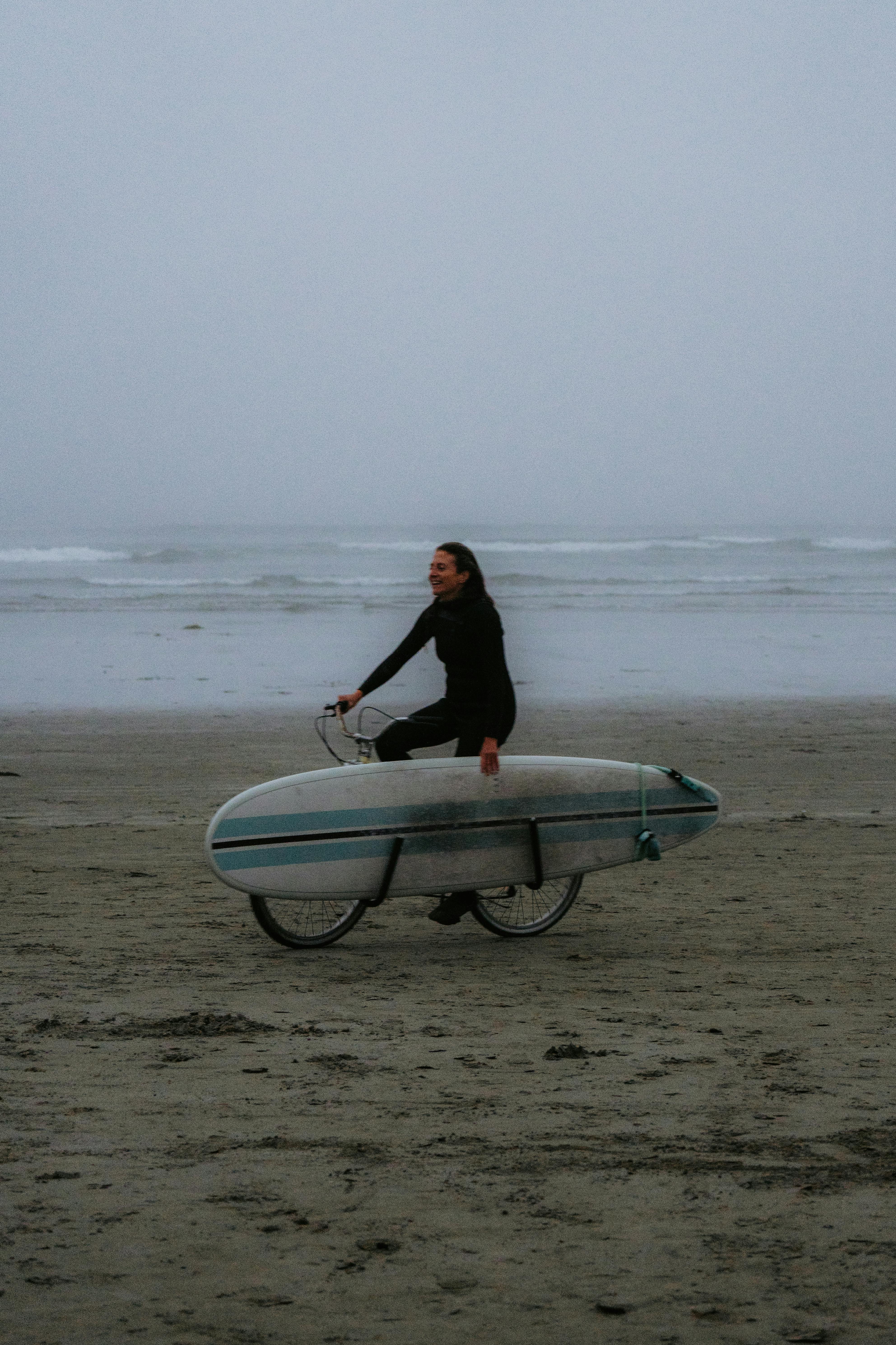 woman riding bike with surfboard