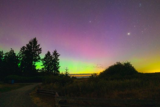 Captivating view of aurora borealis illuminating the night sky over a serene rural landscape.