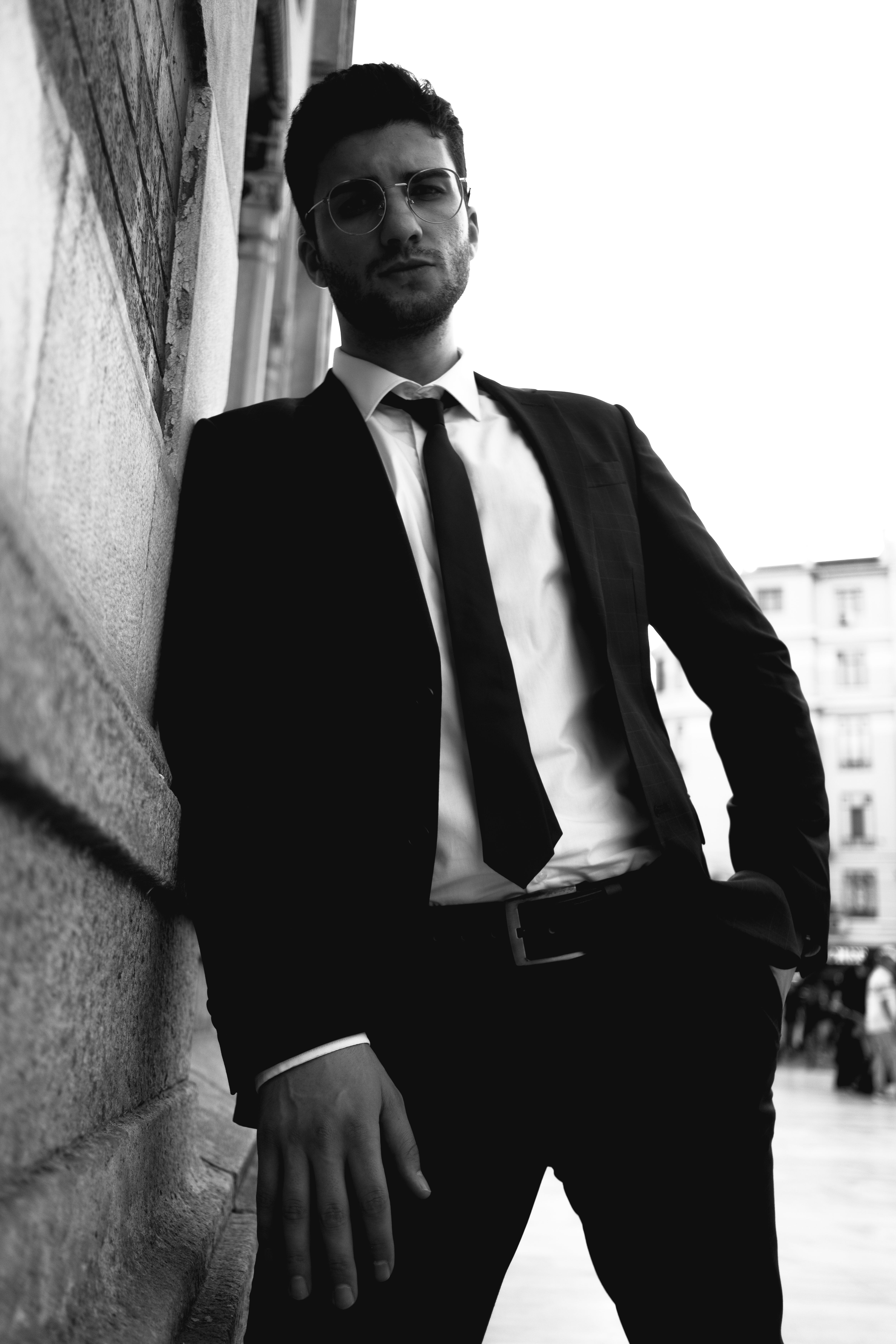 A man in a suit leaning against a wall · Free Stock Photo