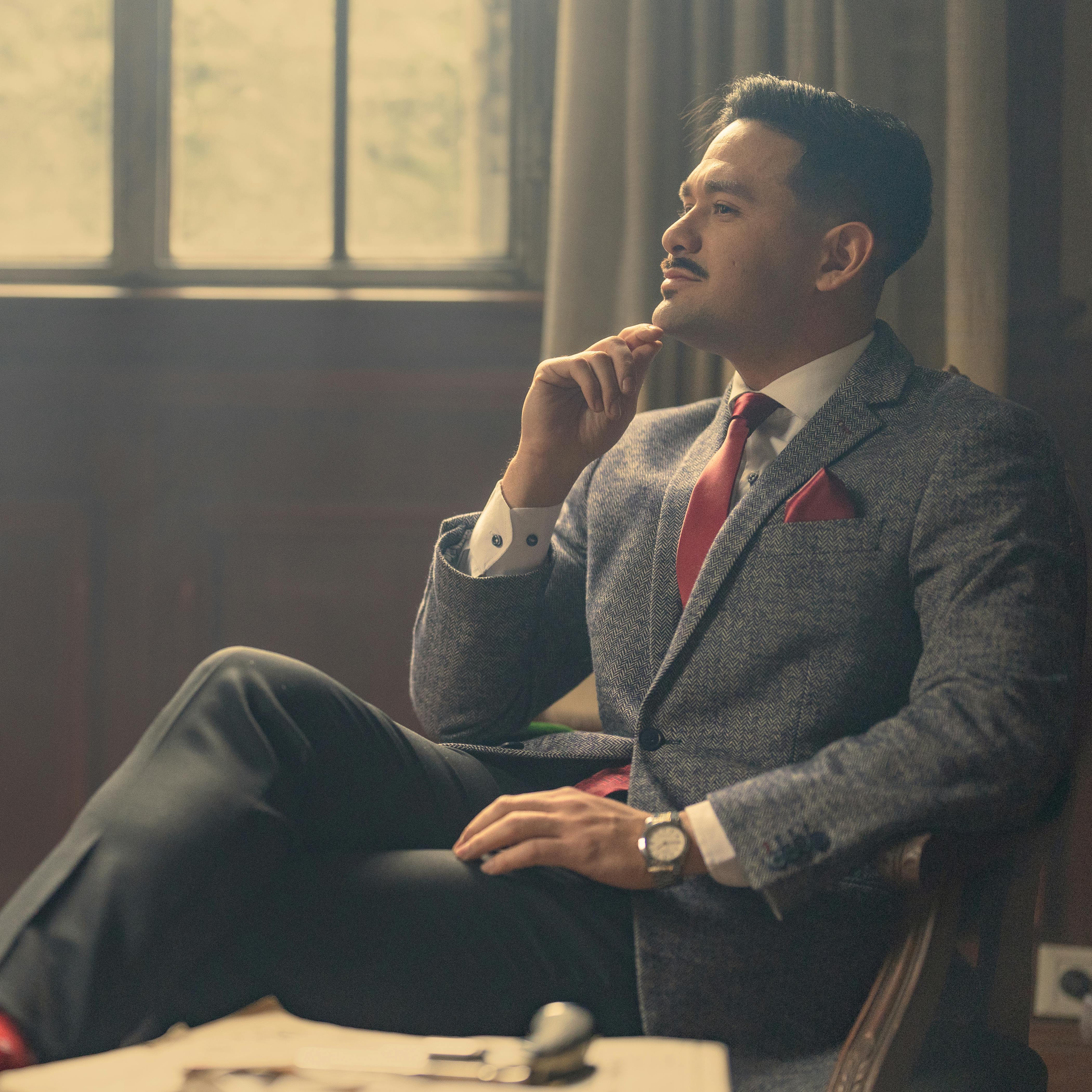 A contemplative businessman in a vintage office setting, wearing a stylish suit with a pensive expression.