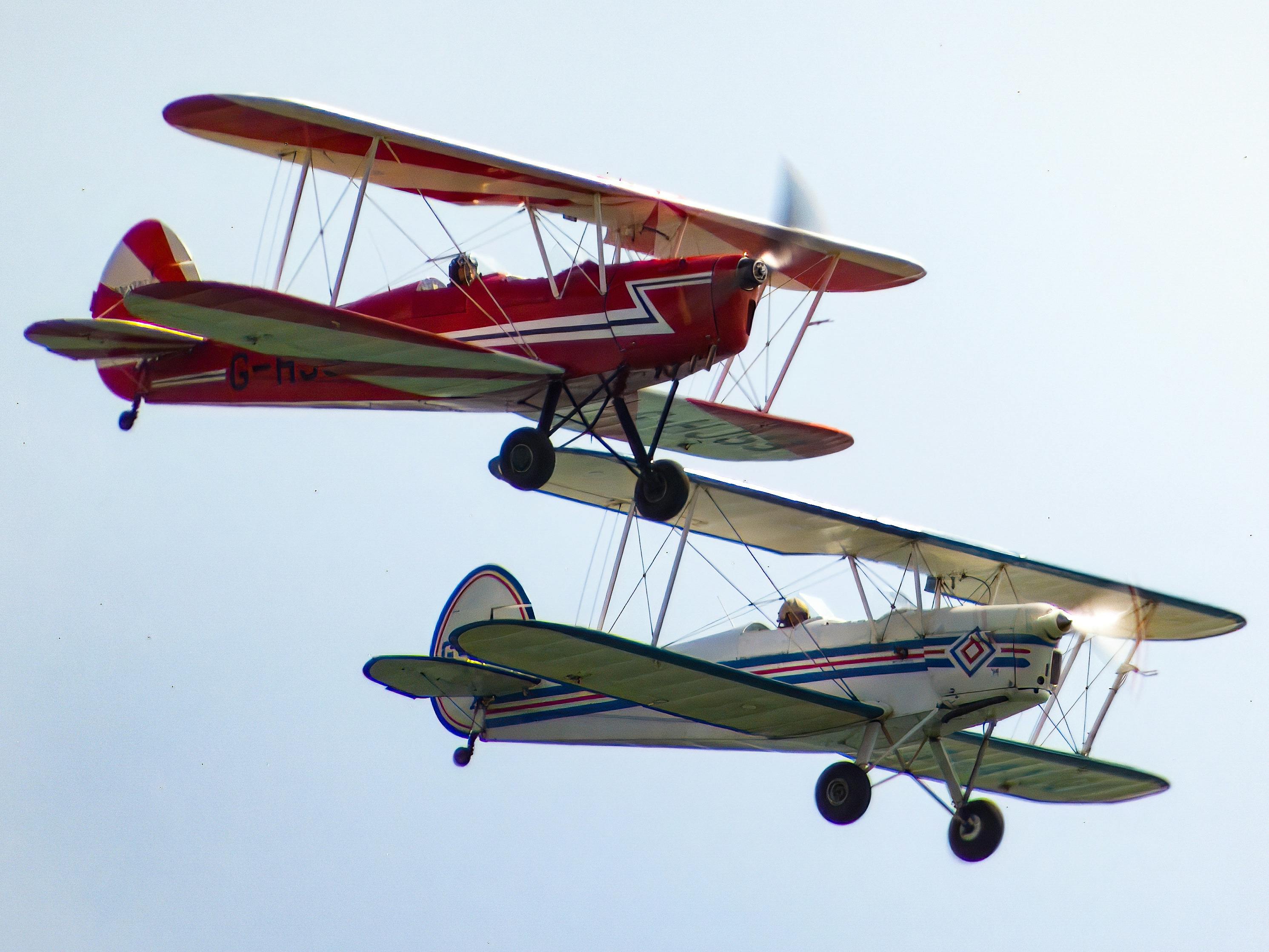 two small airplanes flying in the sky