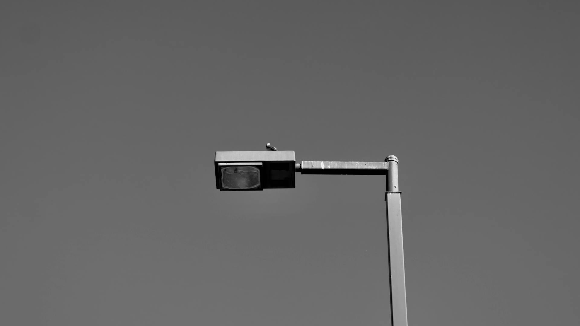 Black and white photo of a street light in a clear sky, emphasizing minimalist design.