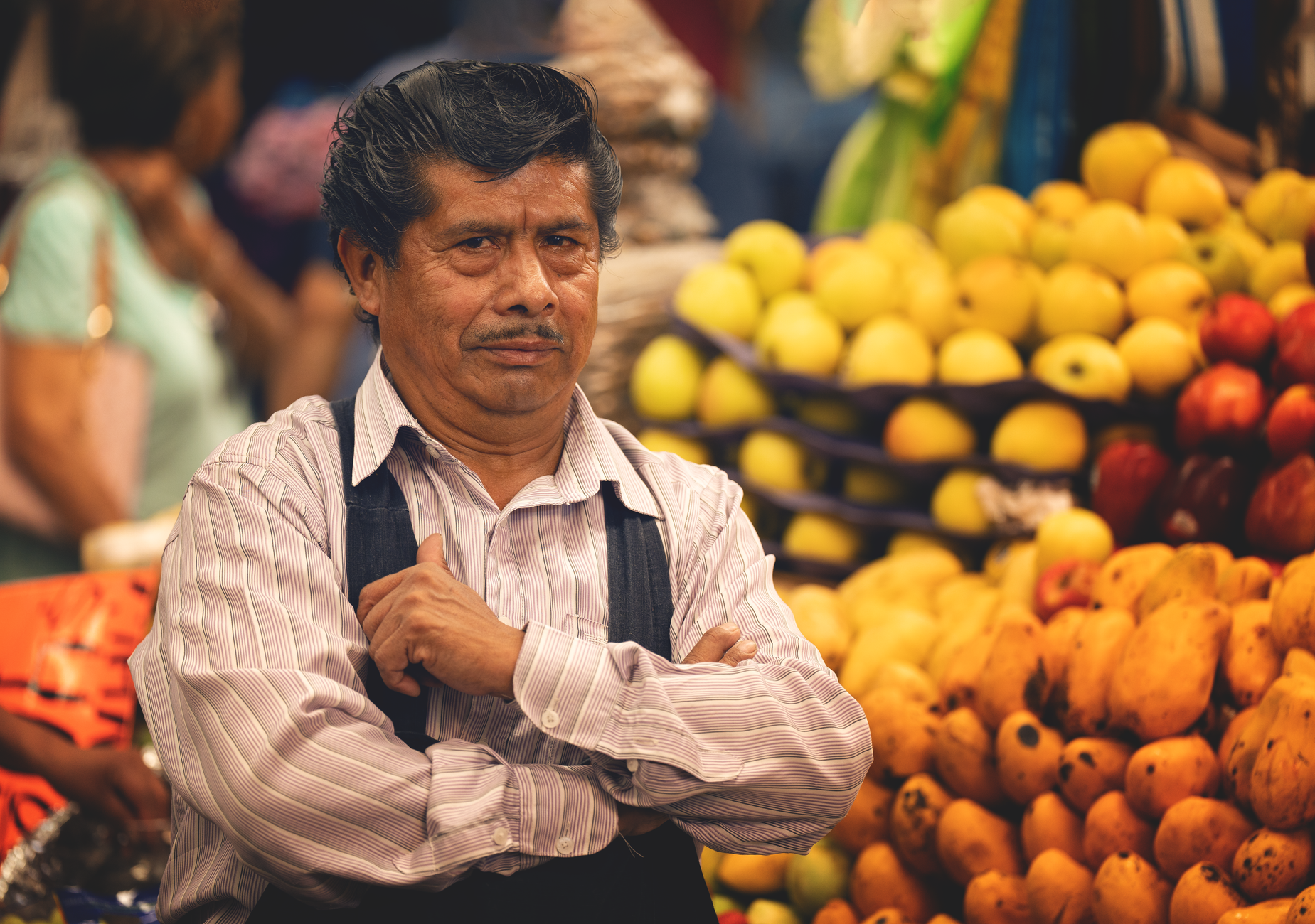 A portrait of a market vendor in Cholula, Mexico, surrounded by colorful tropical fruits.