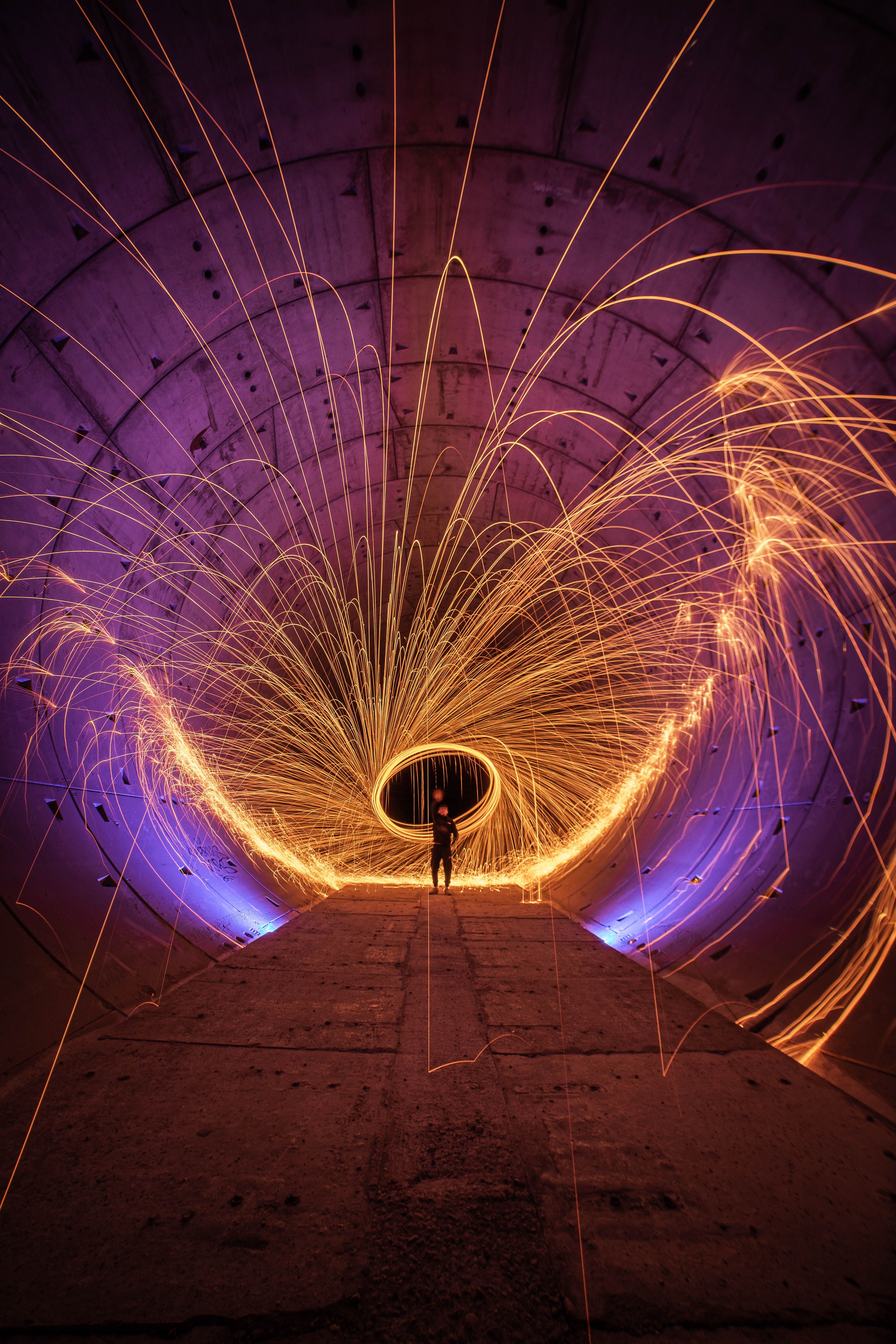 Spectacular light painting with vibrant sparks in an urban tunnel setting.