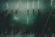 特写镜头捕捉了潮湿玻璃表面的水滴和条纹，创造出抽象的纹理