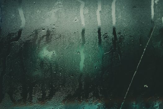 特写镜头捕捉了潮湿玻璃表面的水滴和条纹，创造出抽象的纹理