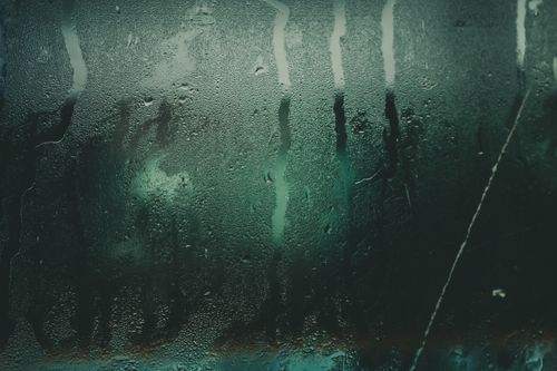 Free Close-up of a moist glass surface with water droplets and streaks creating an abstract texture. Stock Photo