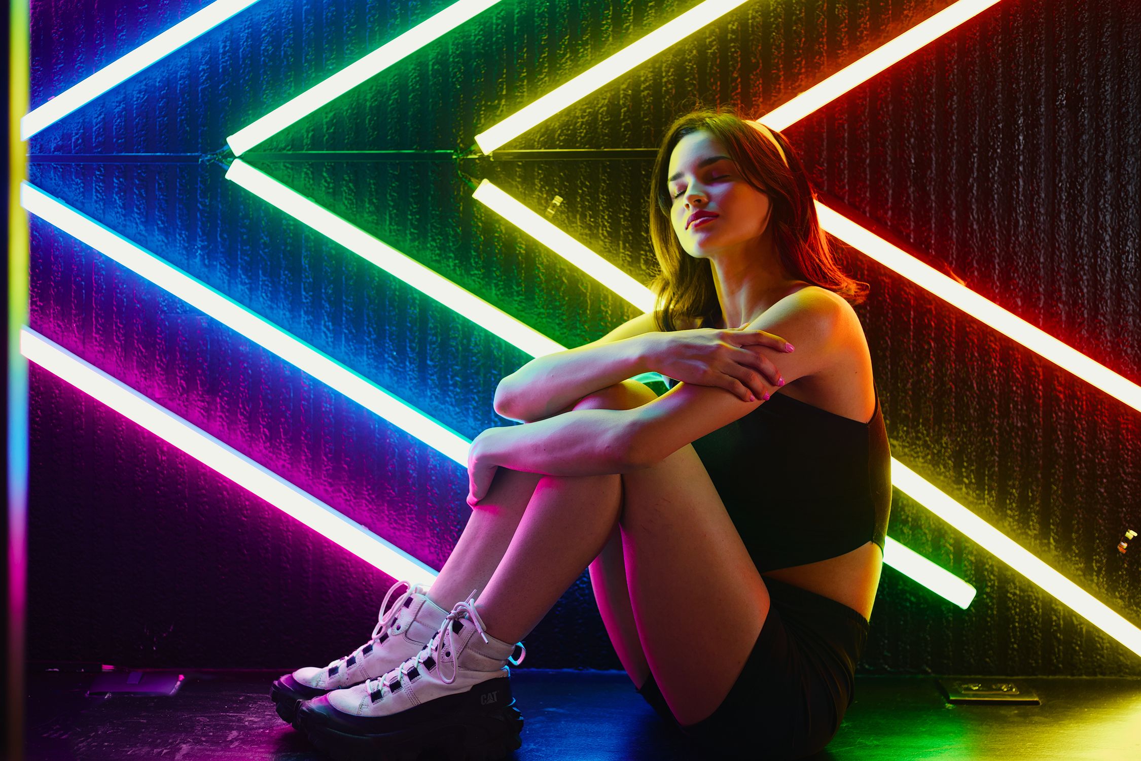 A woman sitting on the floor in front of a neon sign · Free Stock Photo