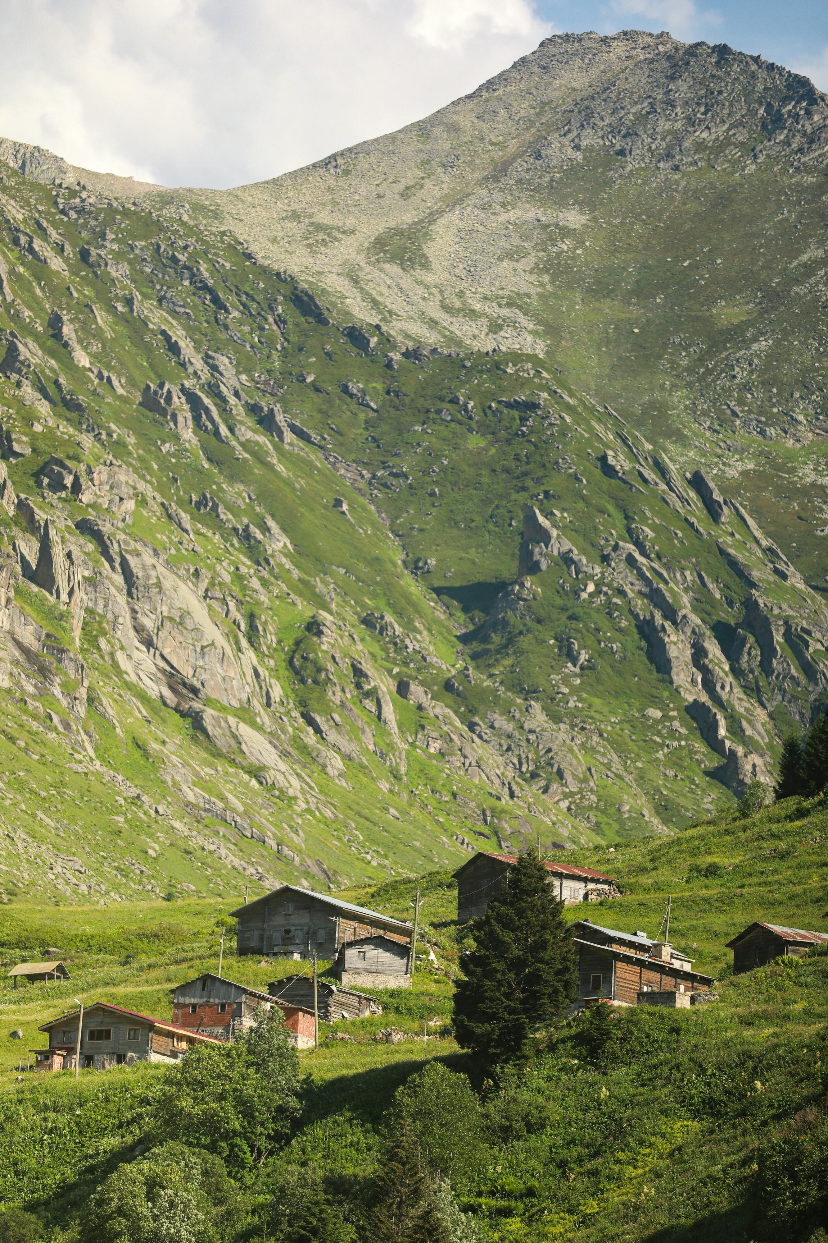 a mountain village with a green grassy hillside