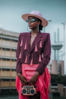 Elegant African woman striking a pose in vibrant urban fashion with bright colors.