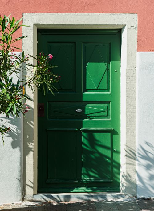 Free Vibrant green wooden door with Mediterranean architecture and floral accents. Stock Photo