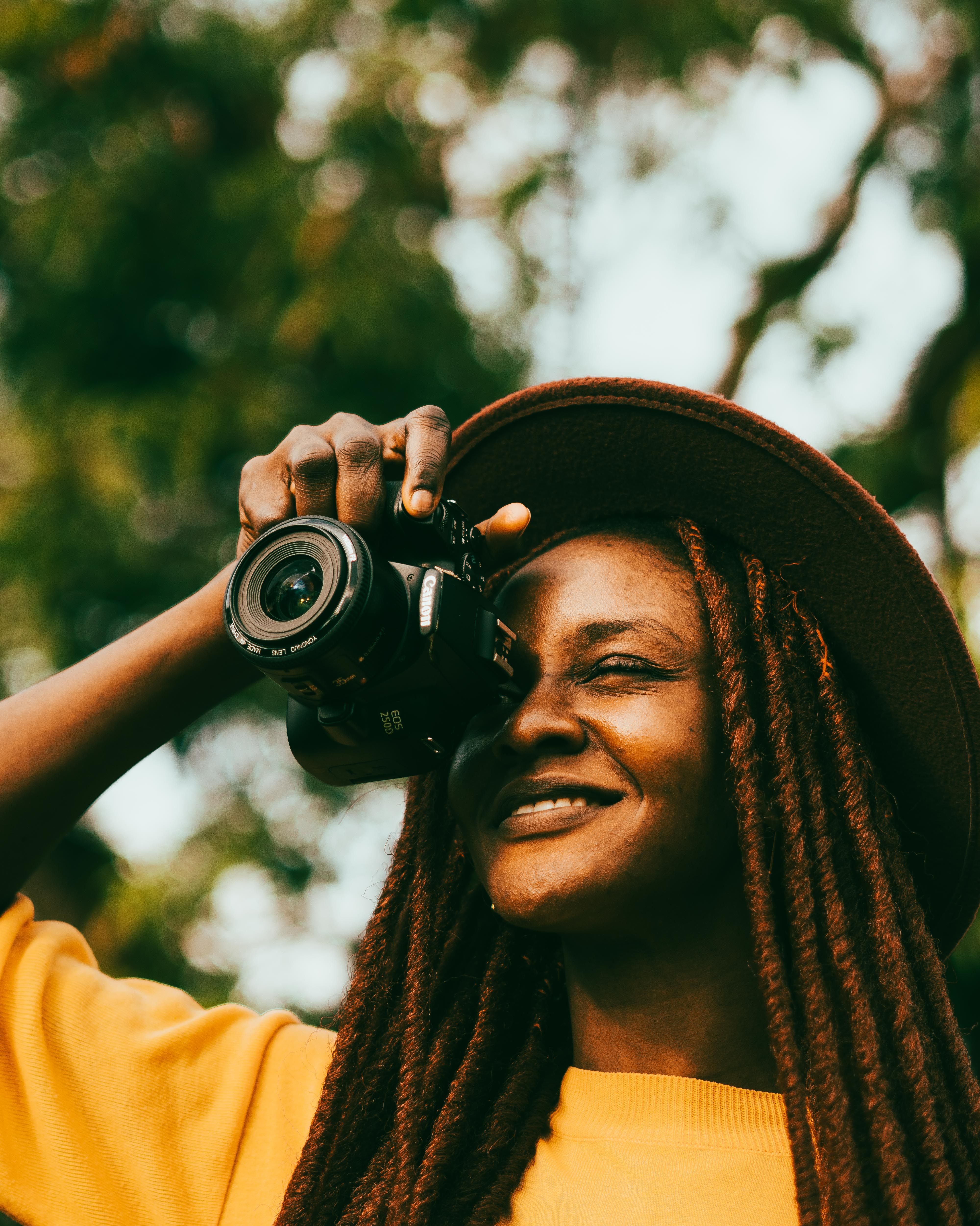 A woman with dreadlocks holding a camera · Free Stock Photo