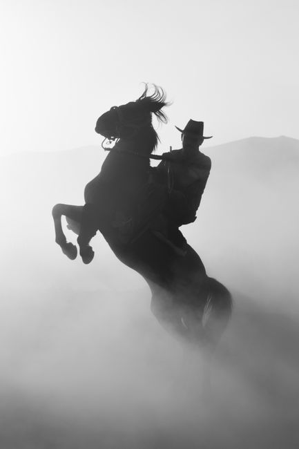 Dramatic silhouette of a cowboy riding a rearing horse in a misty landscape of Kayseri, Turkey.