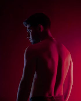 Silhouette of a shirtless man in low light with red backlighting.
