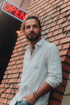 在巴西库里蒂巴，一位时尚男子倚靠在开放标志下的砖墙上